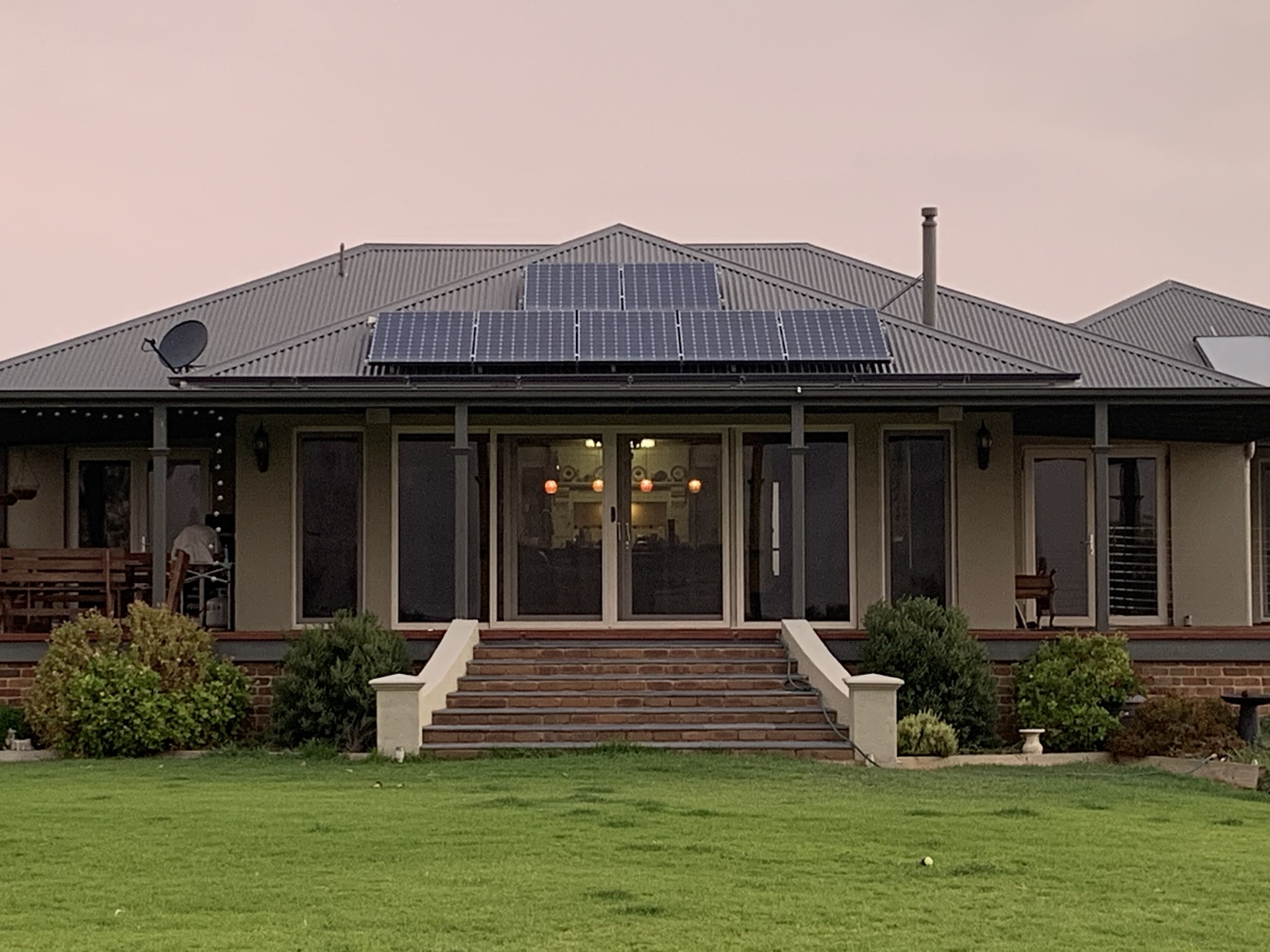 The Lodge at dusk, a long verandah with warm light spilling from the French doors onto the lawn