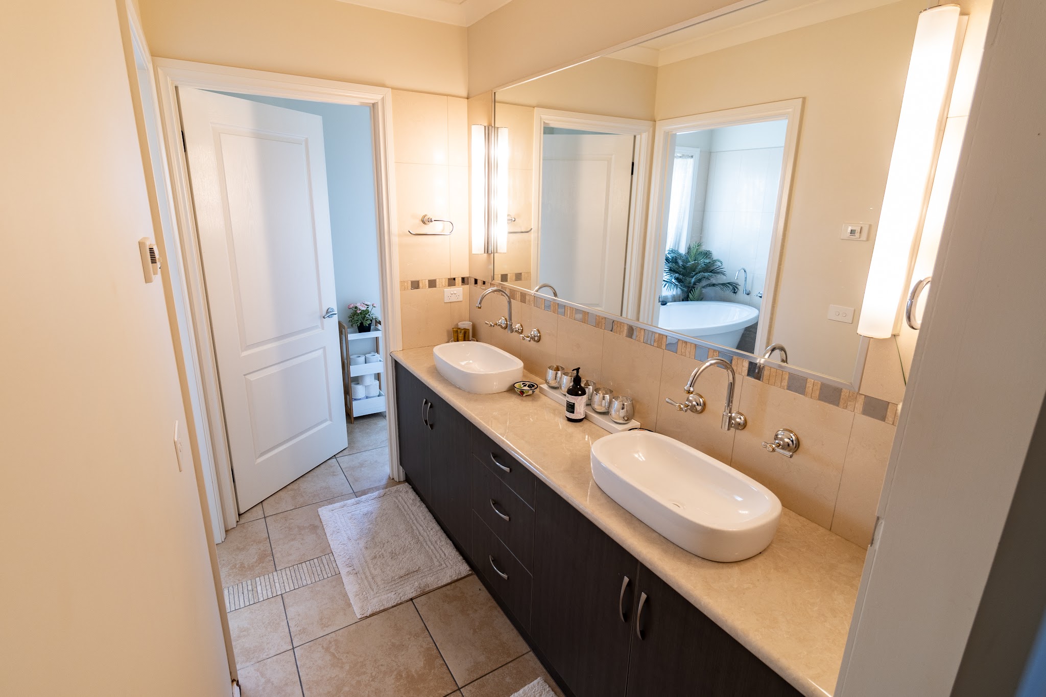A guest bathroom with twin vessel basins and a large mirror